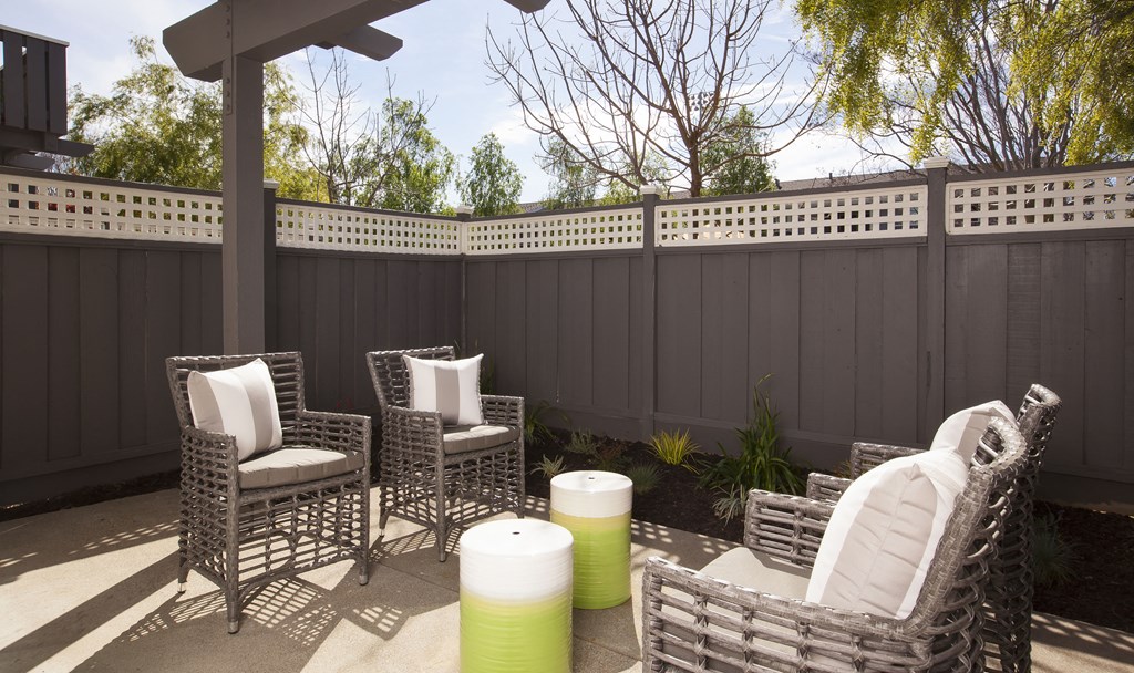 a patio with wicker chairs and a privacy fence