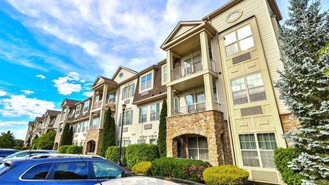 a row of apartment buildings with cars parked in front
