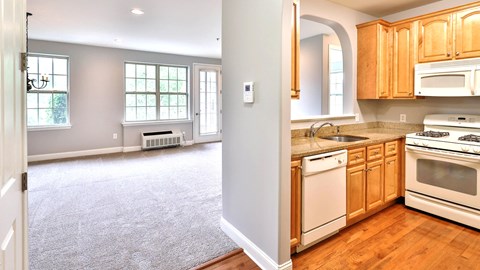 the kitchen and living room of an empty house with wood floors and white appliances