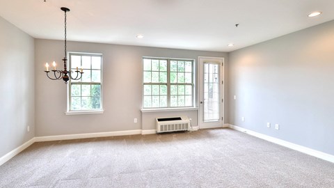 an empty living room with a chandelier and a window