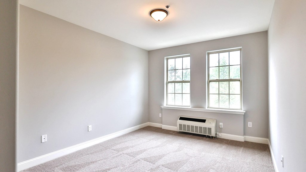 an empty room with a radiator and two windows