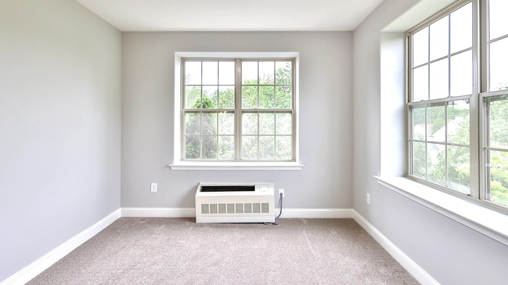 an empty room with a radiator and two windows