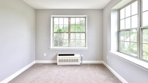 an empty room with a radiator and two windows