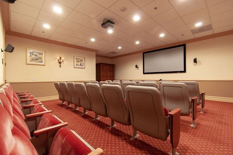 a theater room with a row of chairs and a projection screen