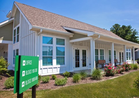 a small white house with a green sign in front of it