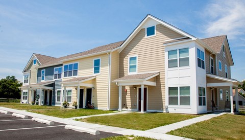 the exterior of a home with tan siding and blue windows