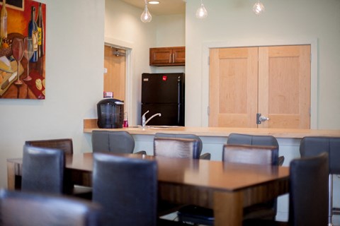 a dining room with a table and chairs and a kitchen with a refrigerator
