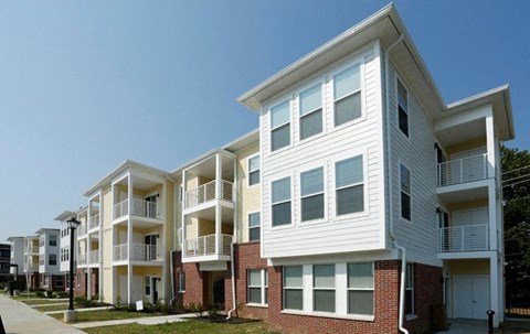a row of white apartments with balconies and a sidewalk