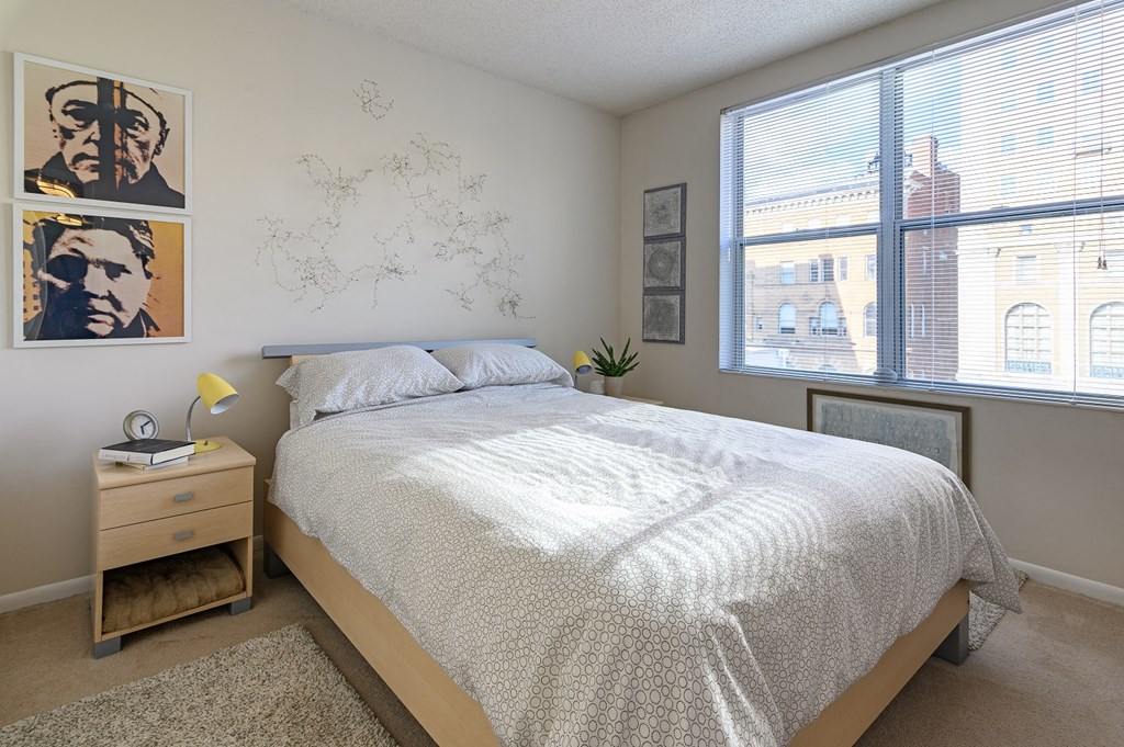 a bedroom with a bed and two large windows