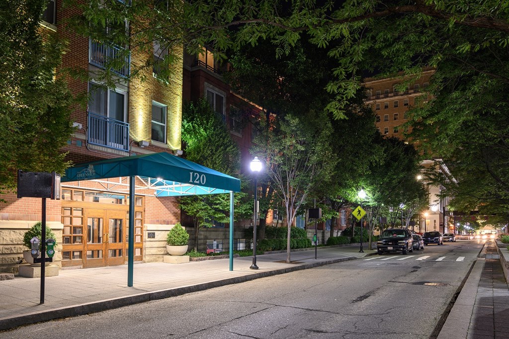 a city street at night with cars parked on the street