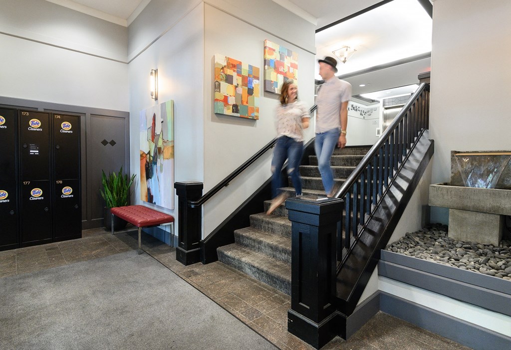 a man and a woman walking down the stairs in a lobby