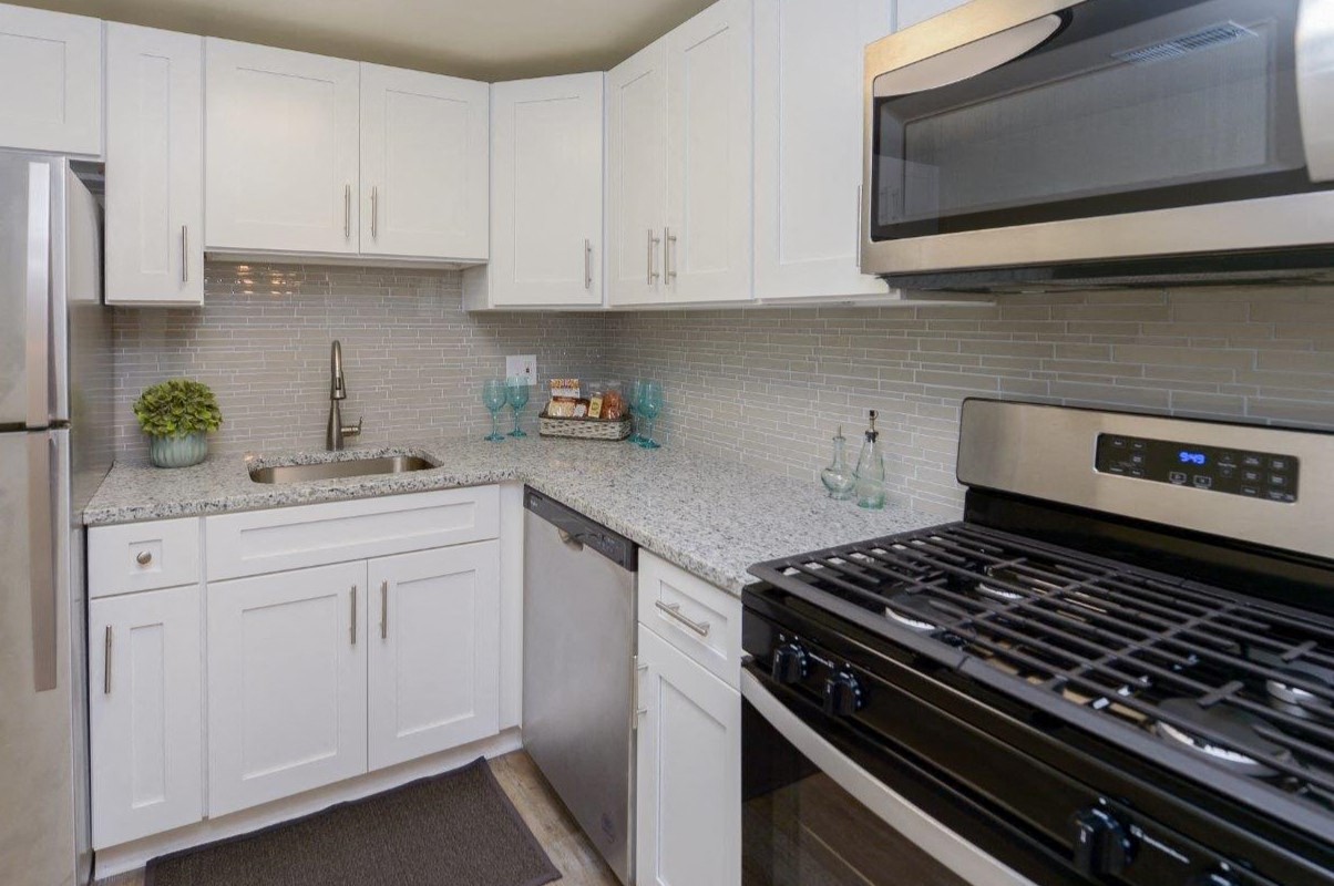a white kitchen with stainless steel appliances and white cabinets