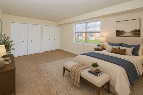 A bedroom with a large bed and a window overlooking a green area.