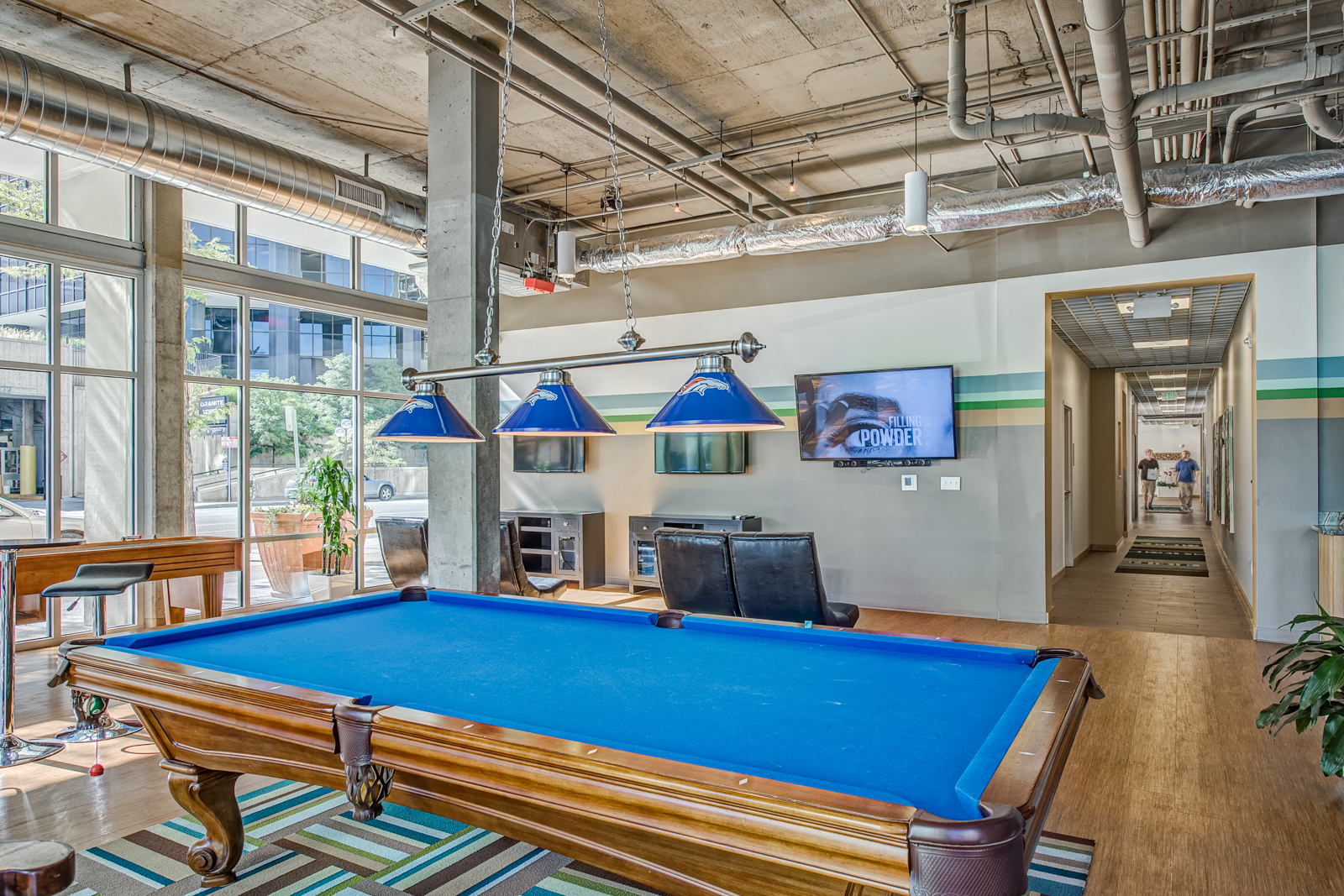 a pool table in a living room with large windows