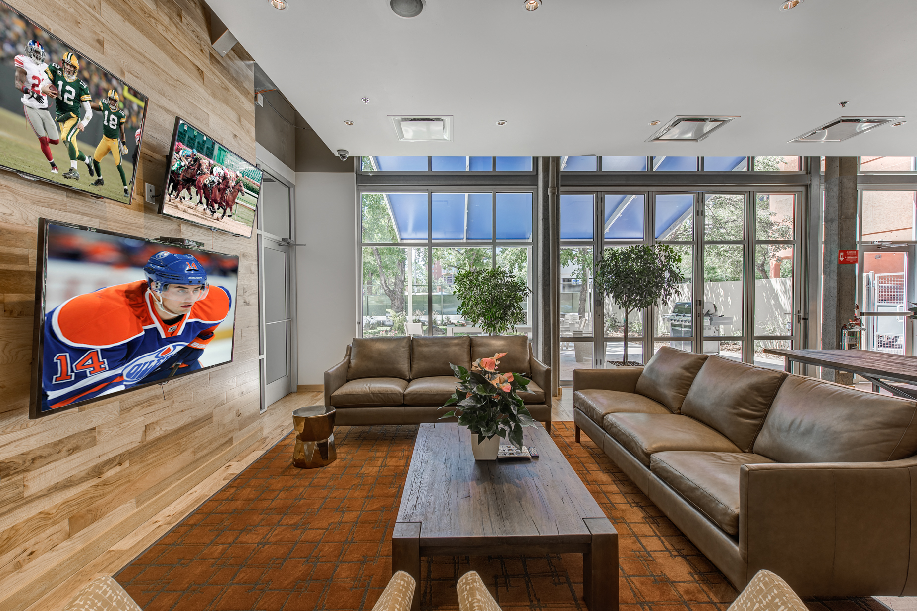 a living room with couches and a coffee table and a large wall of television