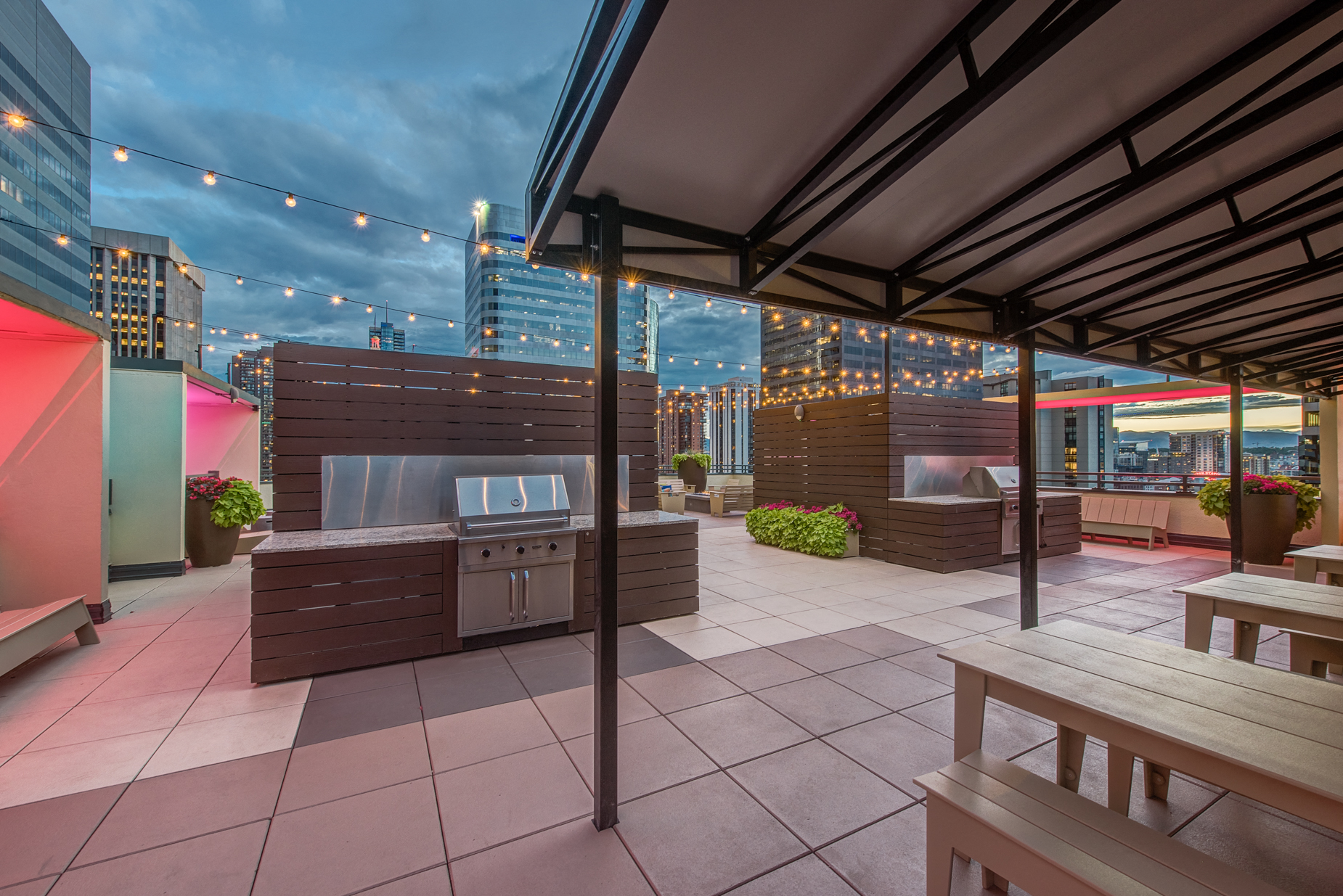 a patio with picnic tables and a barbecue grill on a rooftop