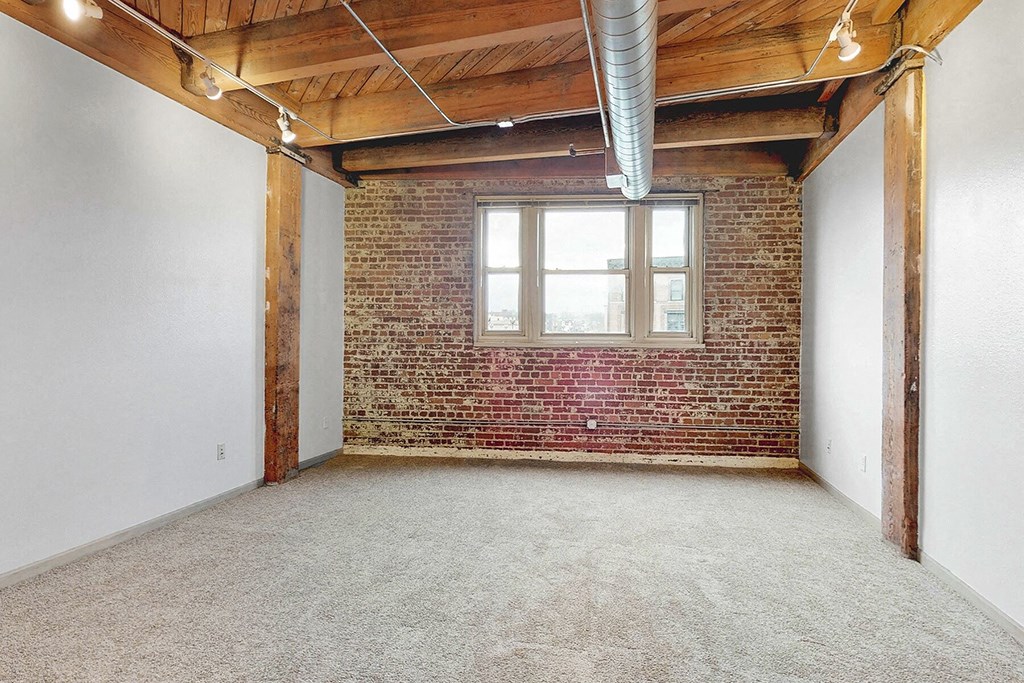 an empty room with a brick wall and a window