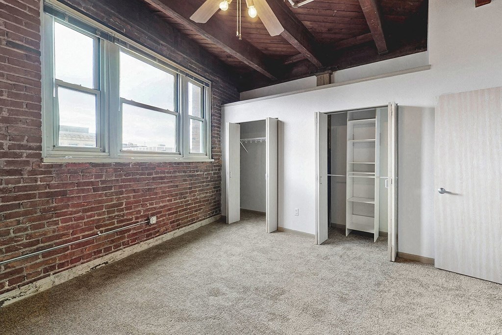 an empty room with a brick wall and a closet