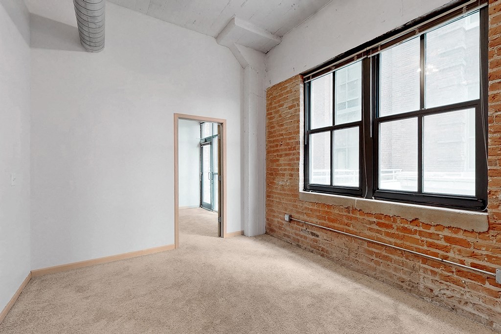 an empty room with a brick wall and a large window
