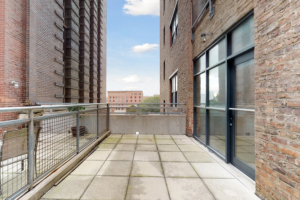 a balcony with a brick building and a glass door
