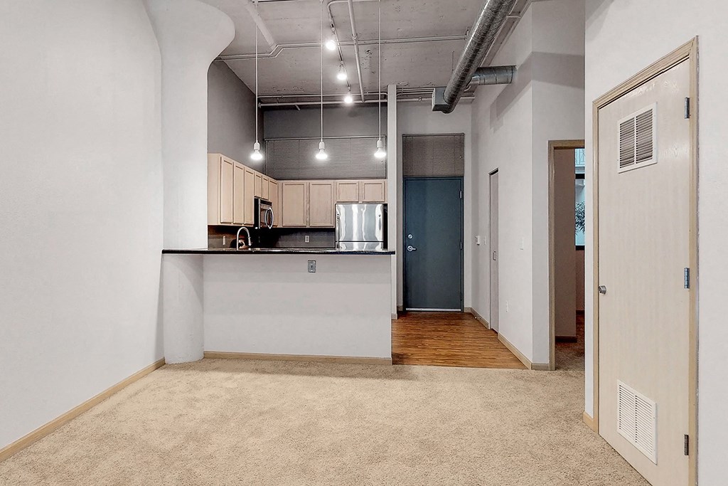a living room with a kitchen and a door to a hallway