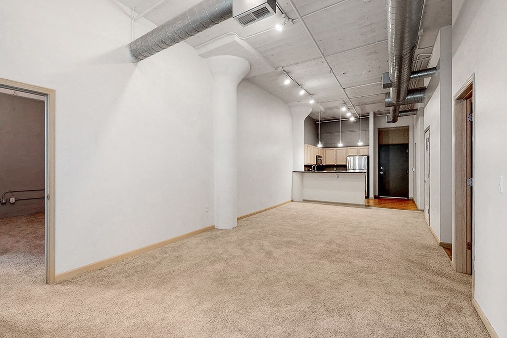 an empty room with a kitchen and a carpeted floor