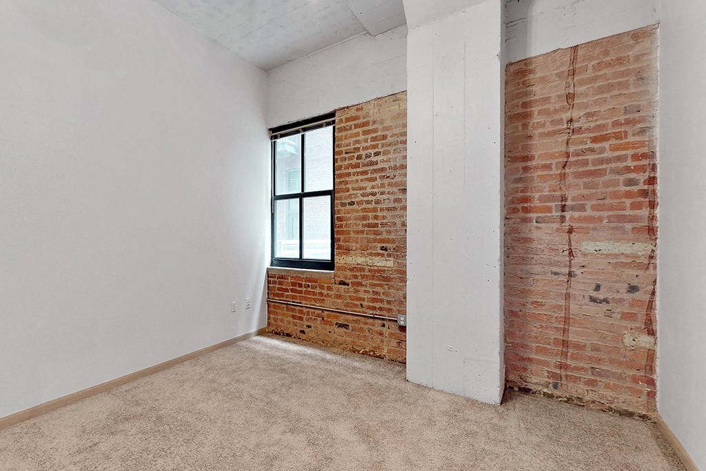 an empty room with a brick wall and a window