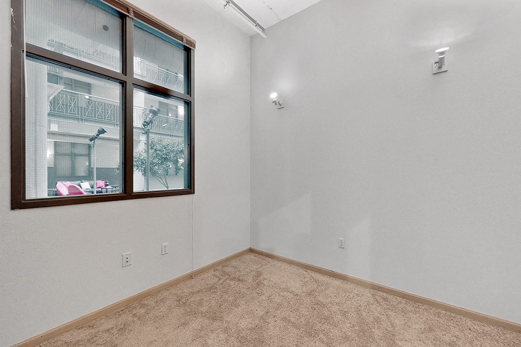 an empty room with a large window and a carpet