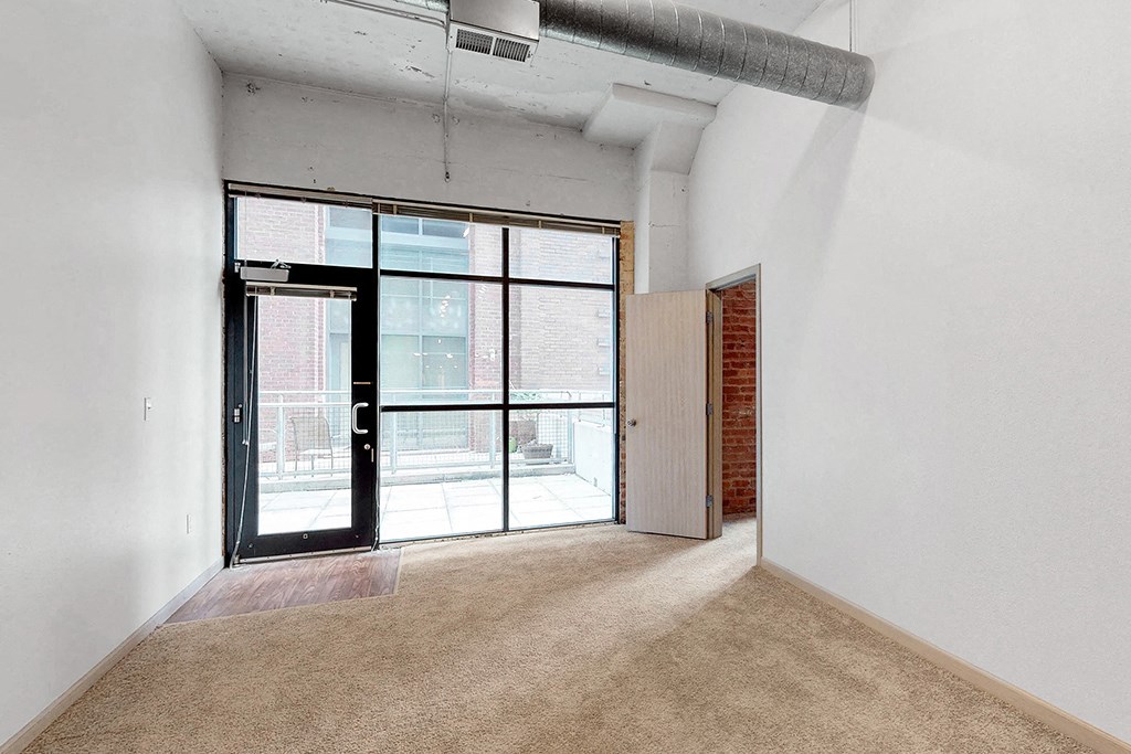 an empty living room with a glass door to a balcony