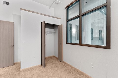 a bedroom with a large window and a door to a closet