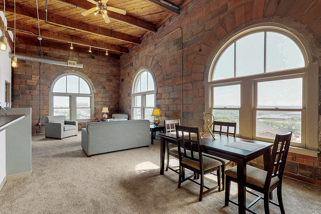 a large living room with a dining room table and large windows