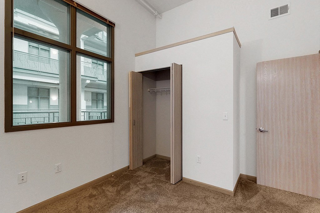 a bedroom with a door to a closet and a window