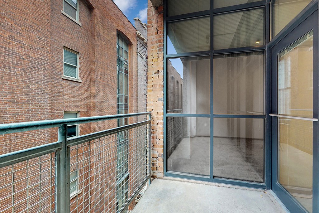 a balcony with a brick building and a glass door