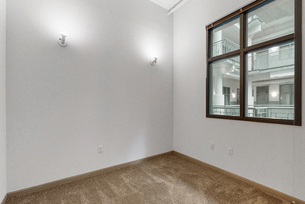 the living room of an apartment with a large window and carpet