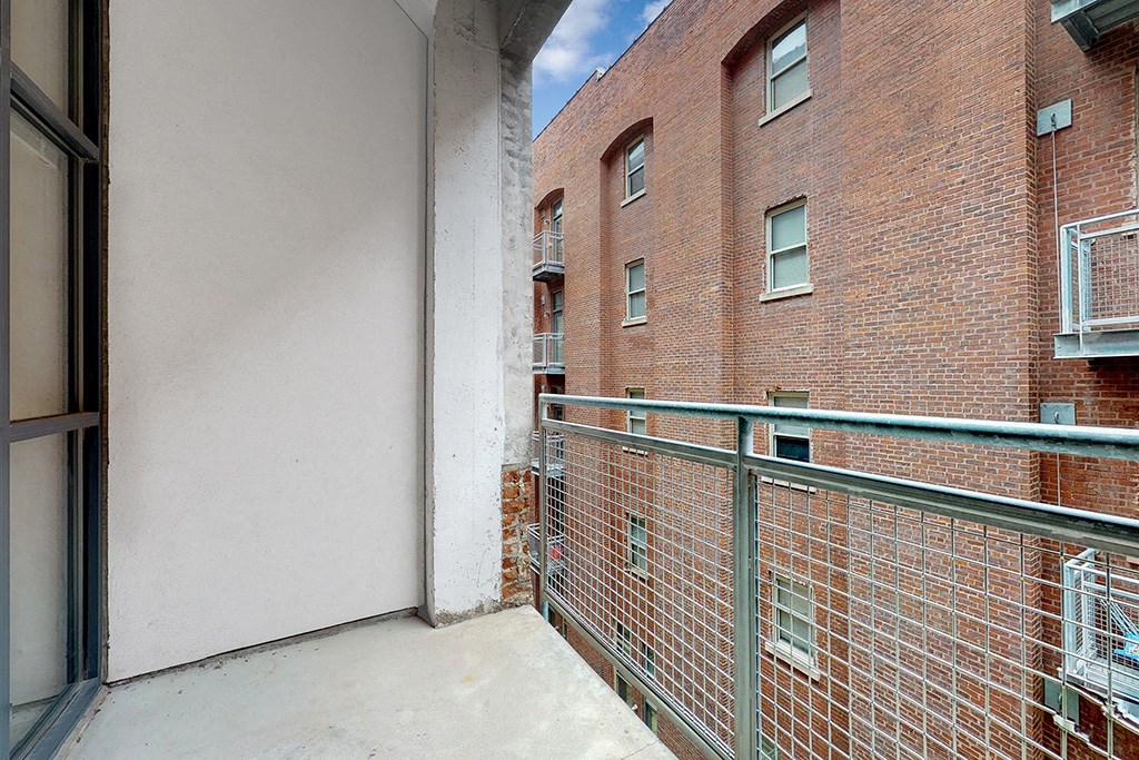 a balcony with a brick building and a green railing