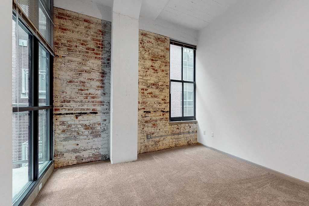 an empty room with a brick wall and a window