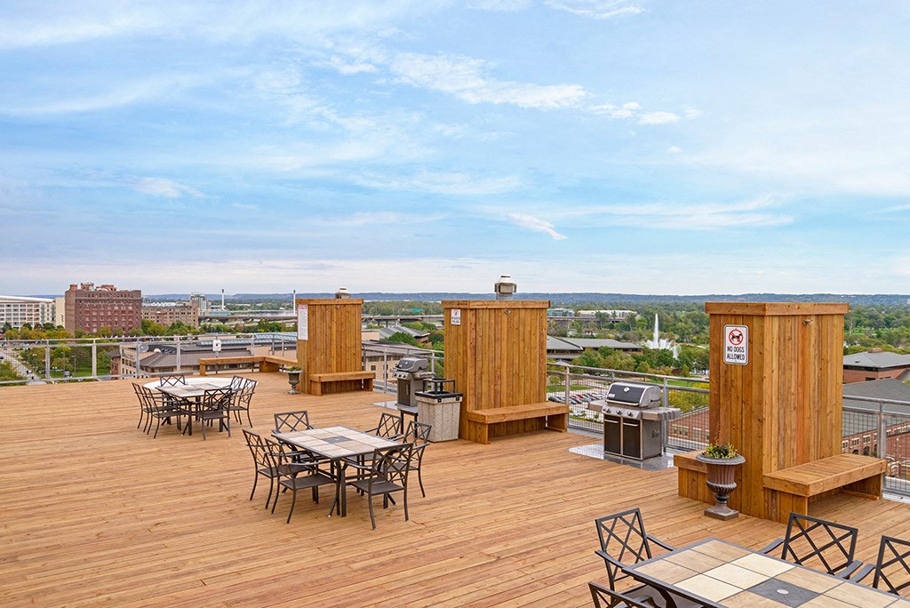 a roof top deck with tables and chairs and a view of the city