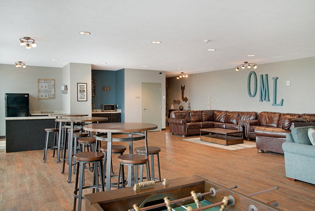 a living room with couches and a bar with tables and chairs