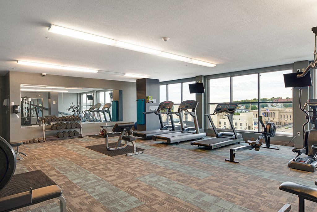 a gym with exercise equipment and windows with a view of the city