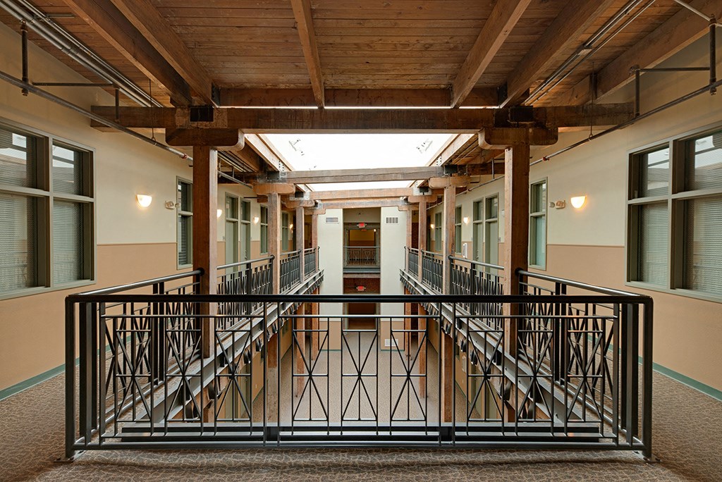 a balcony in a building with a metal railing and wood ceilings