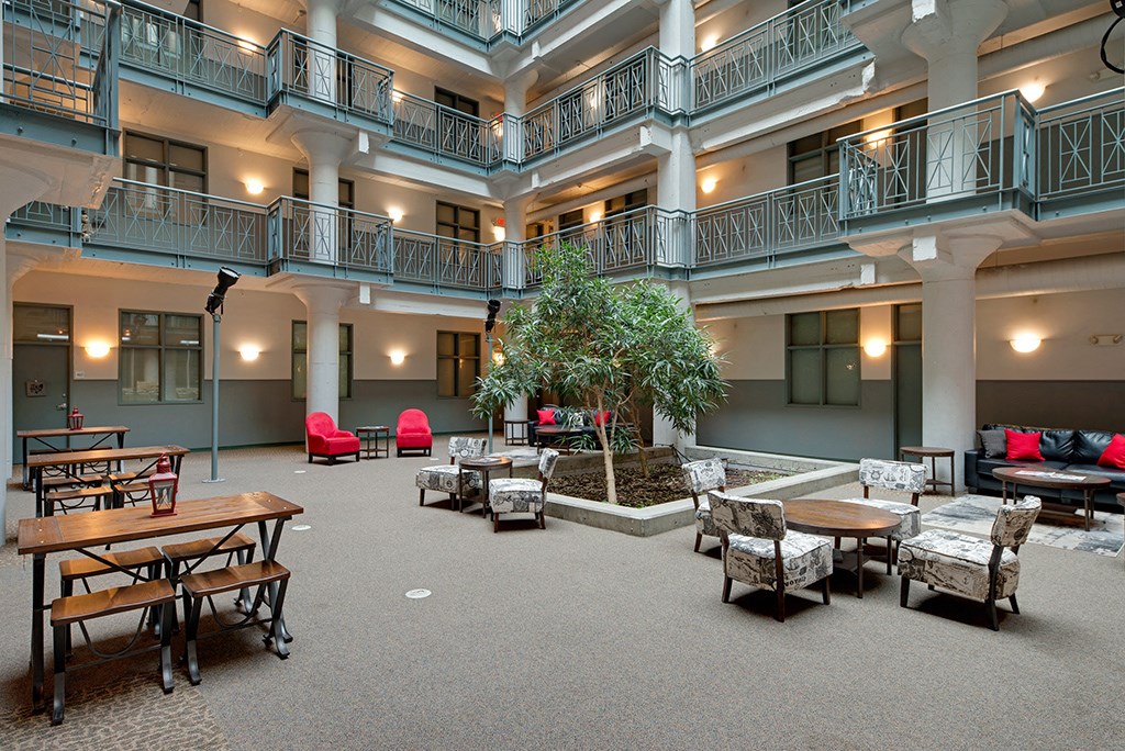 a large lobby with tables and chairs and a tree in the middle