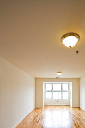 Living room with a 3 panel window, white walls and hardwood floors