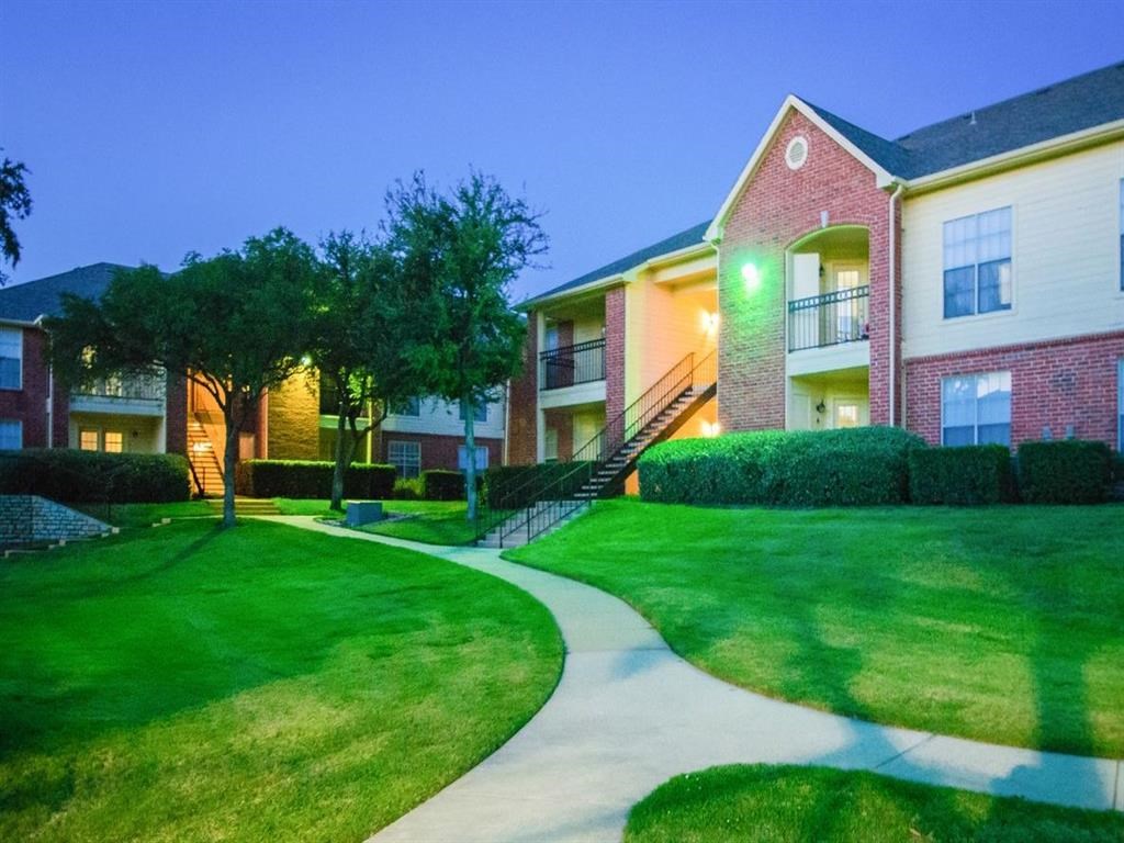 an apartment building with a sidewalk and green grass