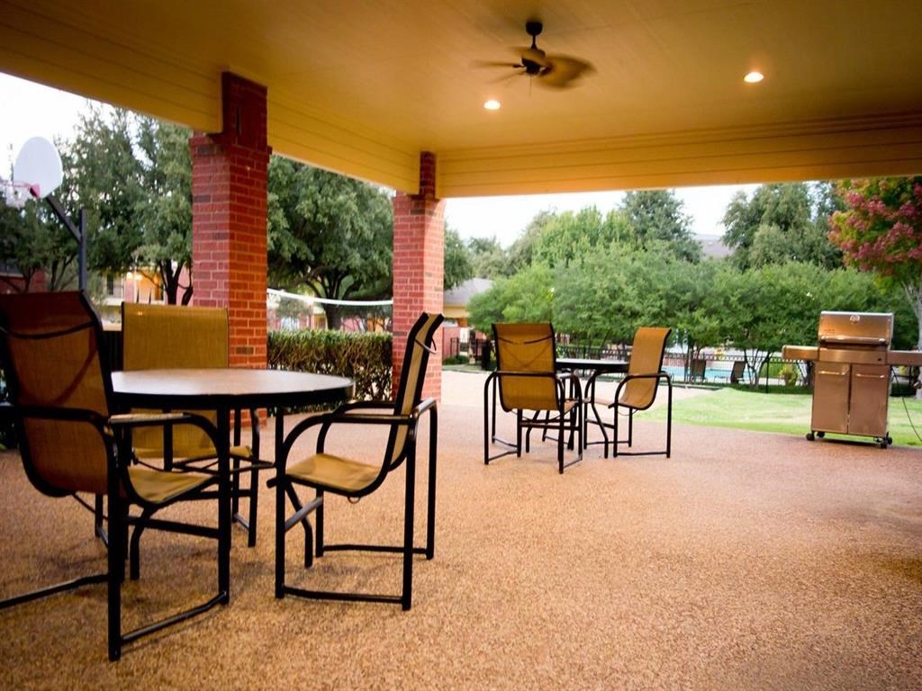 a covered patio with tables and chairs and a fan