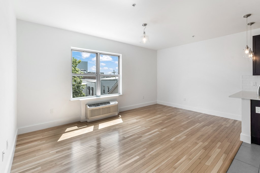 an empty living room with a large window and wooden floors