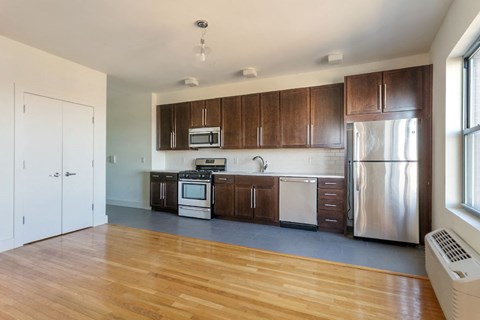 an empty kitchen with wooden floors and stainless steel appliances