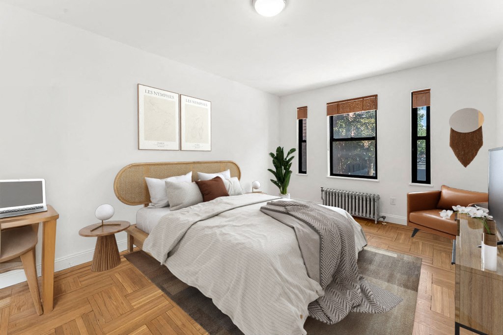 A bedroom with a bed, a desk, a chair, and a plant.