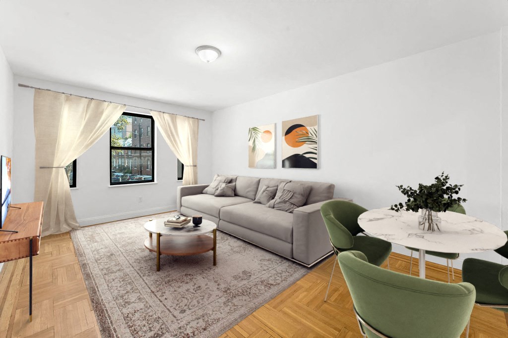A living room with a grey couch, a coffee table, a dining table, and a painting on the wall.