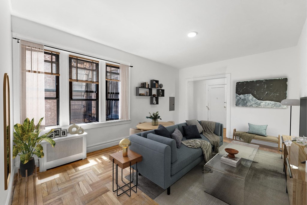 A living room with a grey couch, a coffee table, and a large window.