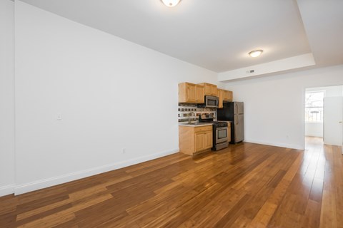the living room and kitchen of an apartment with wood flooring and